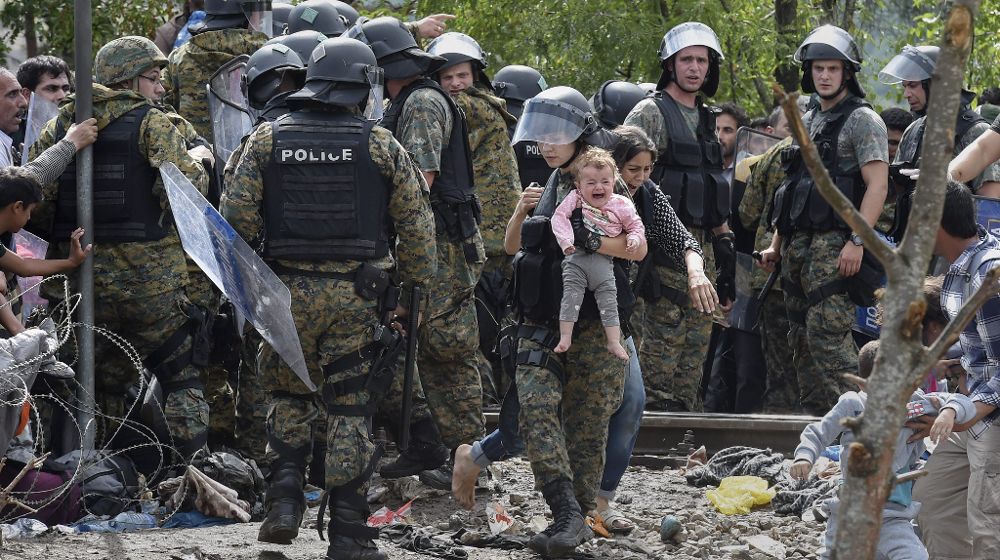 Un policía de las fuerzas especiales macedonias sostiene a un niño mientras los inmigrantes tratan de cruzar la frontera.