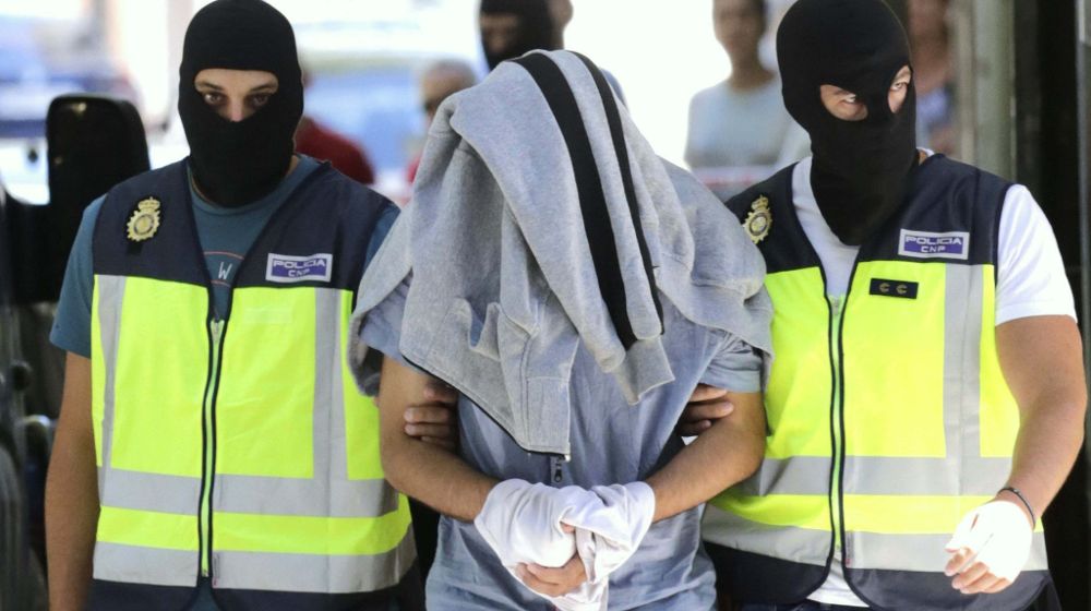 Agentes de la Policía Nacional conducen al detenido con la cabeza tapada, tras concluir el registro de la casa de este supuesto yihadista capturado en la localidad madrileña de San Martín de la Vega.