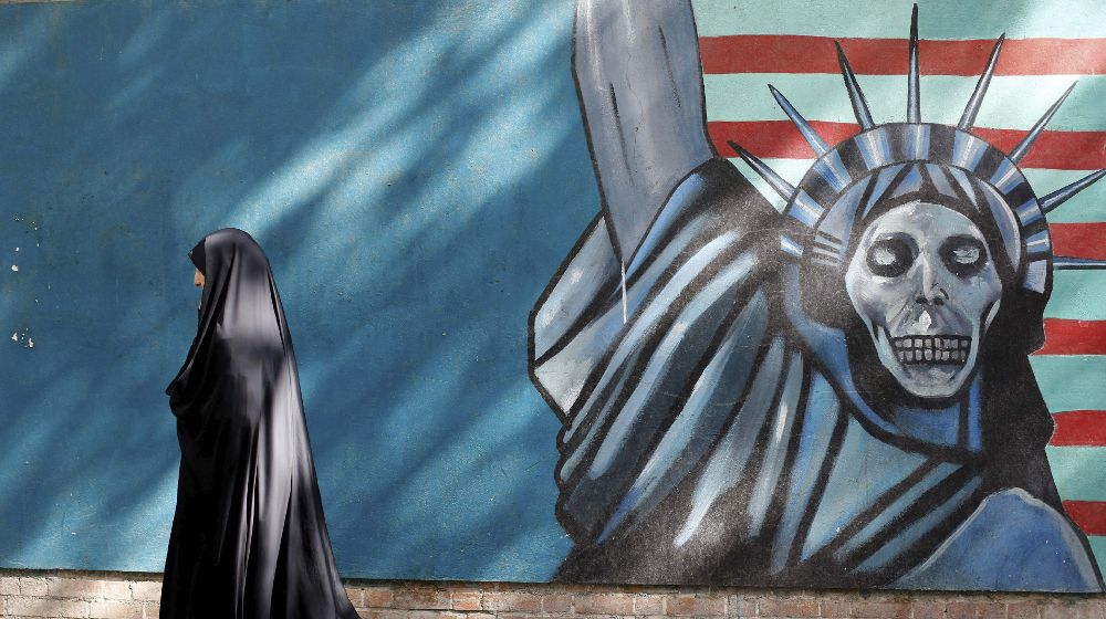 Una mujer camina junto a una caricatura de la Estatua de la Libertad cerca de la antigüa embajada de Estados Unidos en Teherán (Irán).