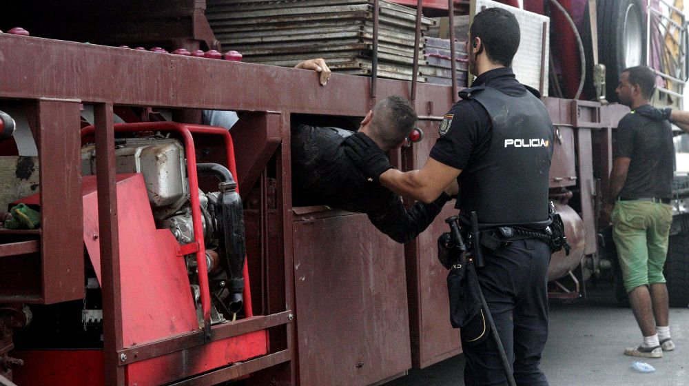 Agentes de la Policía Nacional registran y sacan a los inmigrantes que viajaban ocultos en los camiones de las atracciones.