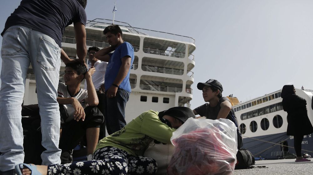 Refugiados esperan a un autobús a su llegada al puerto del Pireo a bordo del buque "Eleftherios Venizelos" cerca de Atenas (Grecia).
