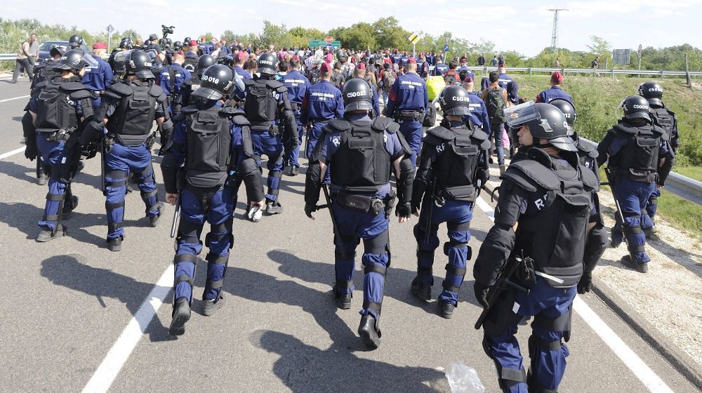 Agentes de policía escoltan a migrantes.