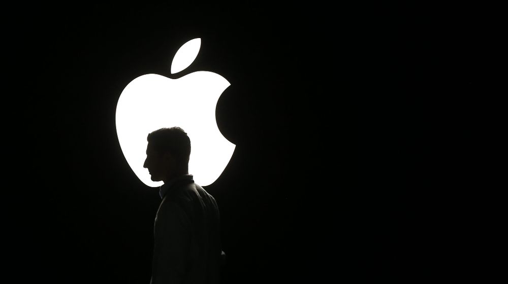La silueta de un hombre se ve frente al logo de Apple.