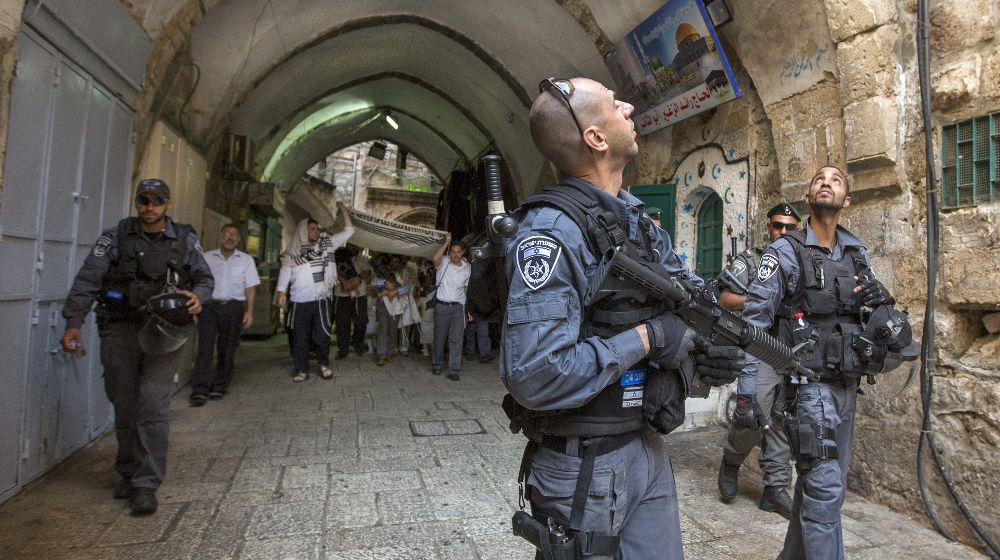 Policías fronterizos israelíes revisa los altos de los edificios mientras escoltan a colonos judíos, que viven en el barrio musulmán de Jerusalén y se dirigen al Muro de las Lamentaciones.