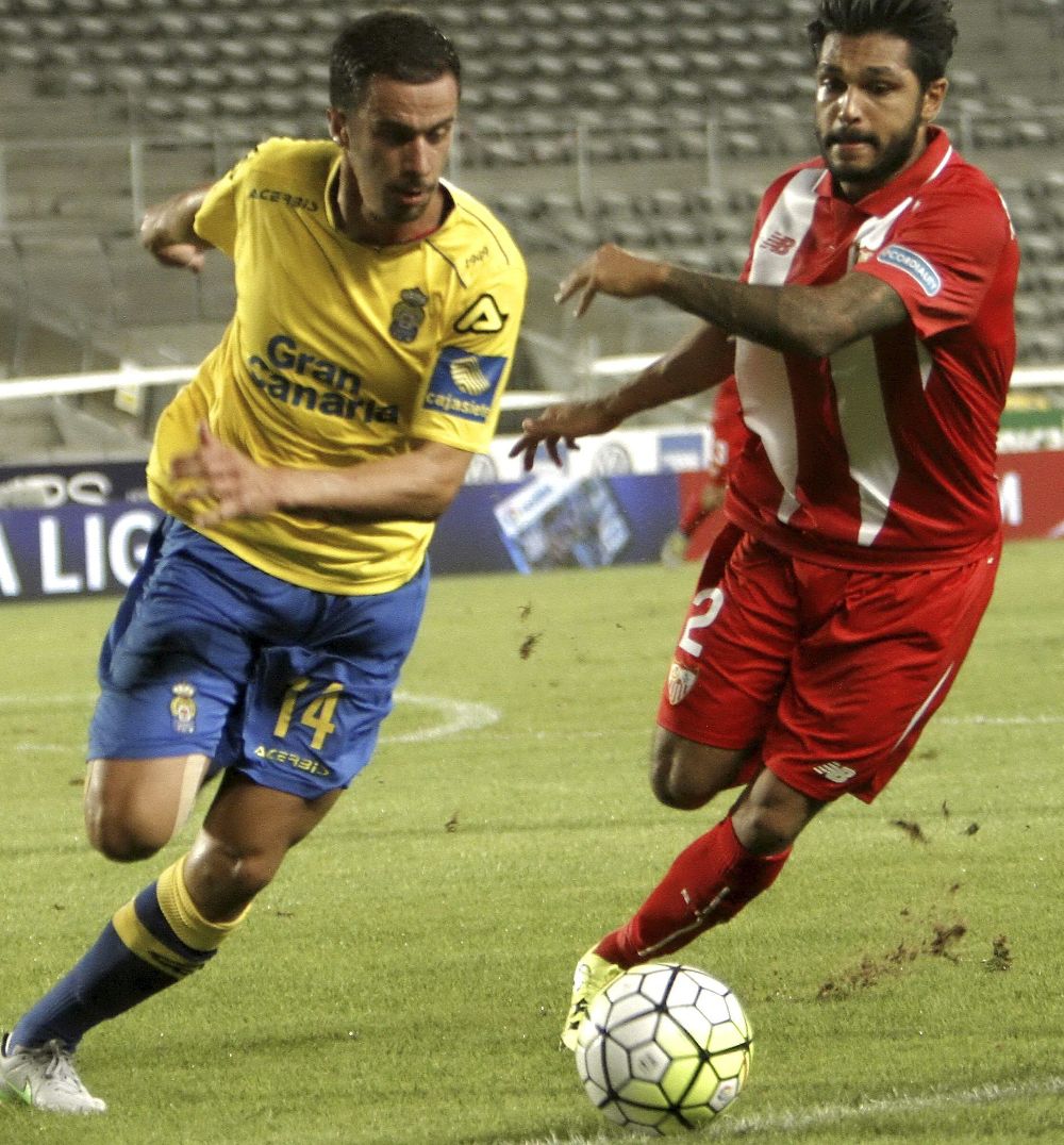 El centrocampista de la U. D. Las Palmas, Hernán Santana (i), se lleva el balón ante el defensa francés del Sevilla, Benoît Trémoulinas.