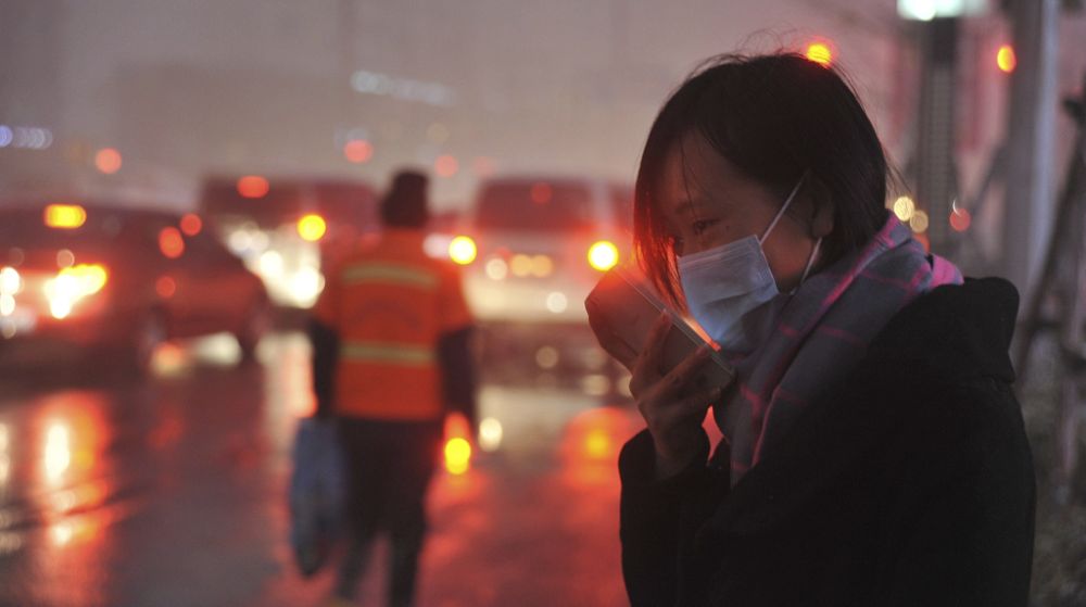 Una mujer habla por teléfono mientras se cubre el rostro con una mascarilla en Shenyang (China) ayer, 8 de noviembre. El norte de China está registrando niveles récord de contaminación después de que las autoridades hayan encendido la calefacción central, generalmente alimentada por carbón.