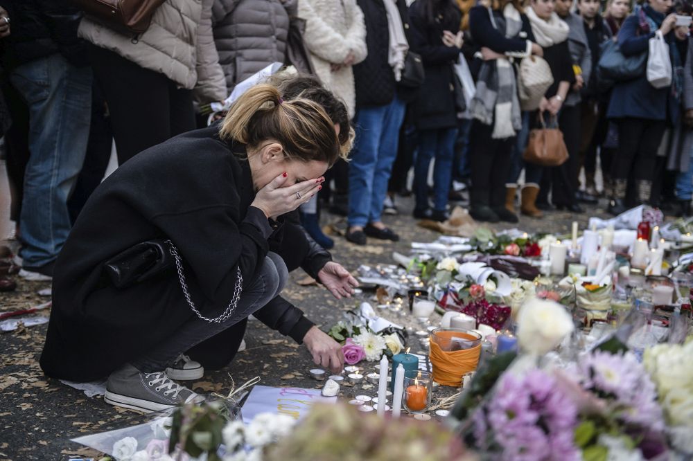 Varias personas colocan flores y velas en memoria de las víctinas de los atentados del pasado viernes, ante la sala de fiestas Bataclan de París, Francia, hoy, 16 de noviembre de 2015.