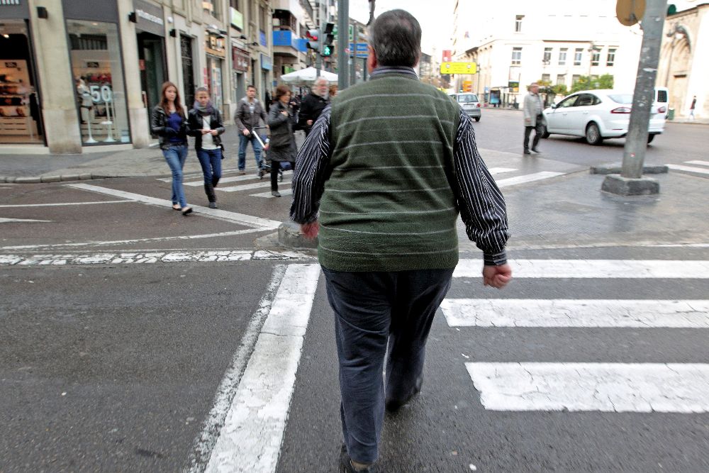 Un hombre con sobrepeso cruza,una calle.
