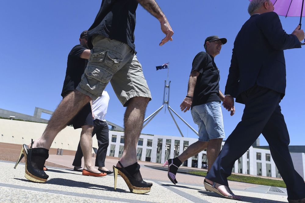 Funcionarios del Departamento de Asuntos Exteriores de Australia caminan en zapatos de mujer a las puertas del Parlamento durante la campaña "camina en sus zapatos", para concienciar sobre el problema de la violencia de género hoy, 25 de noviembre, en Canberra.