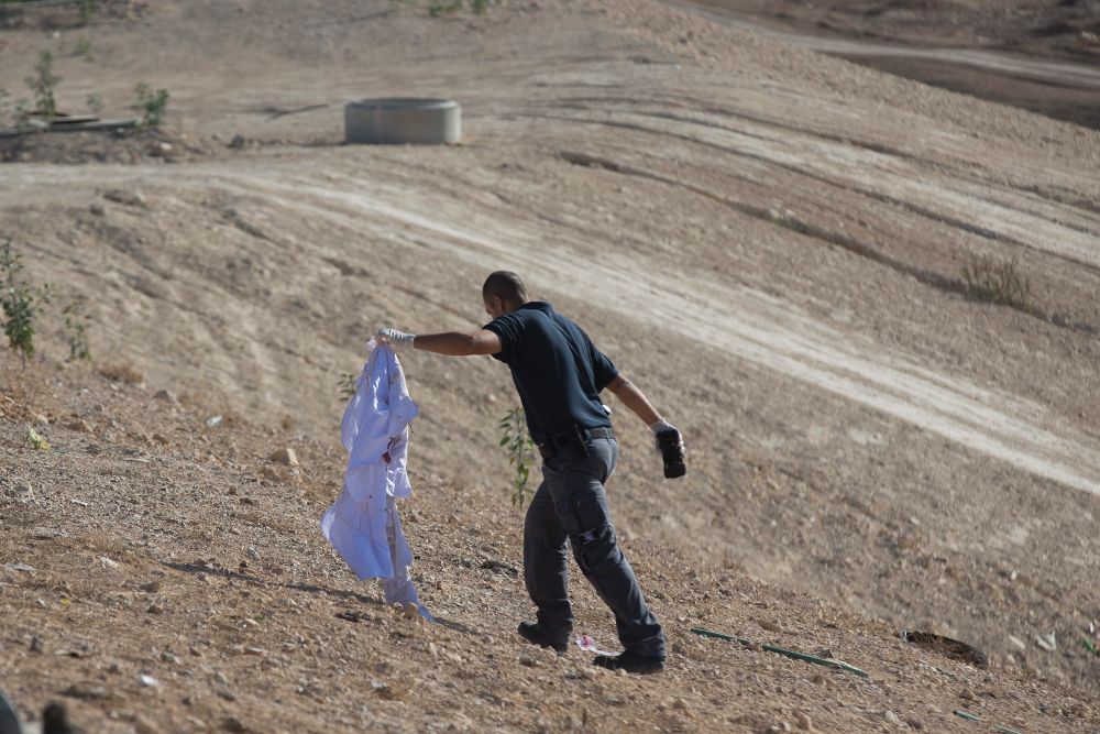 Un policía carga con la camisa de un palestino tras abatirlo a tiros .