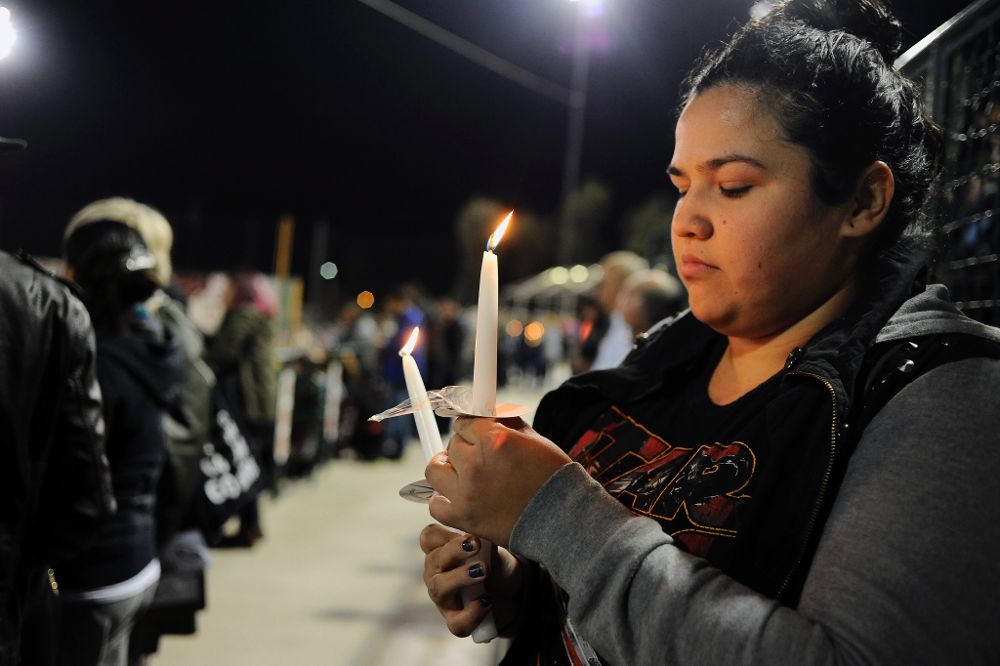 Una mujer sostiene una vela encendida hoy, jueves 3 de diciembre de 2015, en una vigilia por las víctimas de un tiroteo en San Bernardino, California (EE.UU.).