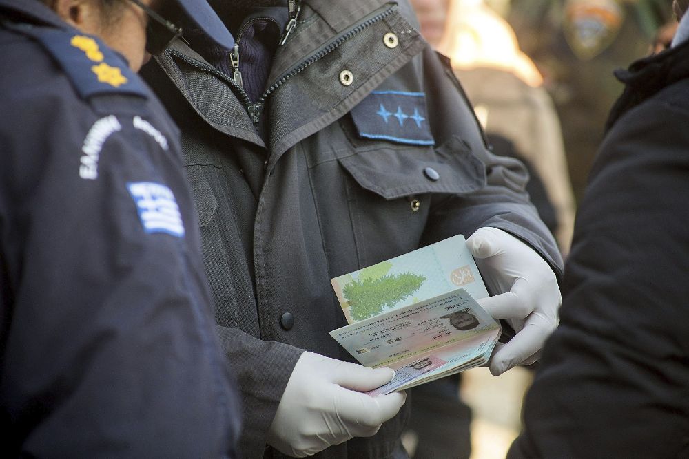 Un agente de la policía griega verifica la documentación de los refugiados antes de que crucen la frontera entre Grecia y Macedonia.