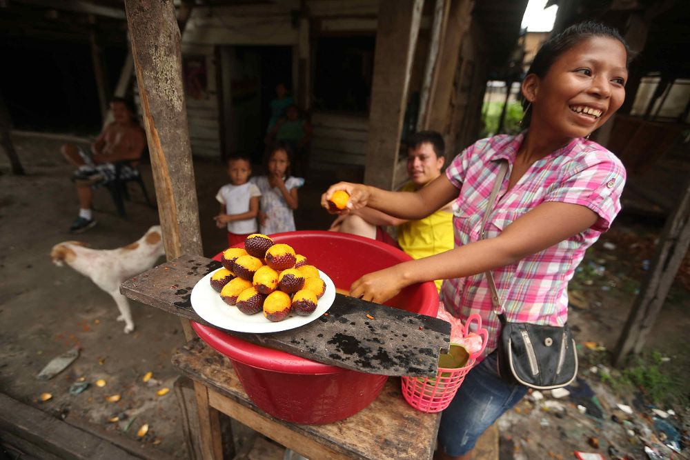 Una mujer pelando el fruto amazónico conocido como el "agüaje" en un calle del barrio Belén, en Iquitos (Perú).