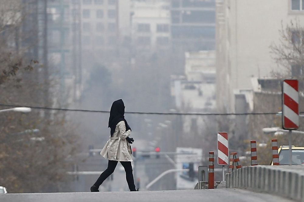 Una mujer camina por una calle bajo una espesa niebla en Teherán, Irán.