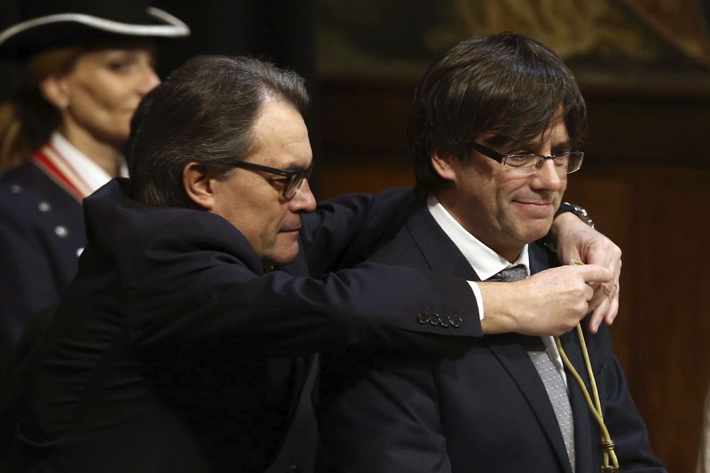 El expresidente de la Generalitat, Artur Mas (i), impone la medalla representativa del cargo al nuevo presidente de la Generalitat, el independentista Carles Puigdemont.
