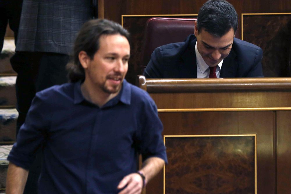 El líder de Podemos, Pablo Iglesias, pasa delante del escaño del secretario general del PSOE, Pedro Sánchez, tras votar para la elección del presidente del Congreso.