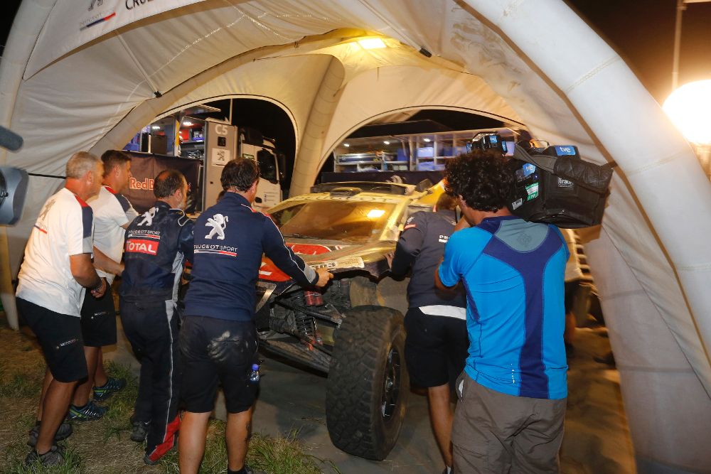 El equipo del español Carlos Sainz empujando su vehículo, luego de abandonar por un problema mecánico durante la décima etapa del rally Dakar Belén-La Rioja (Argentina).