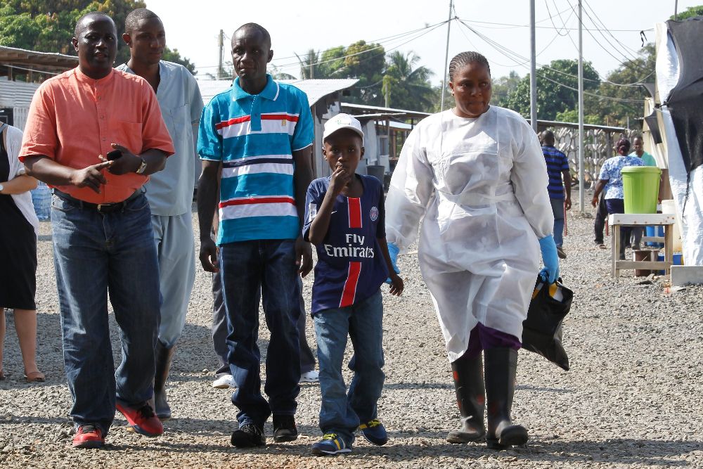 El sobreviviente de ébola Abraham Gbotoe (C), 10, y su padre, Nathan (3-i), se retira de una ceremonia después de ser declarados oficiálmente libres de ébola.