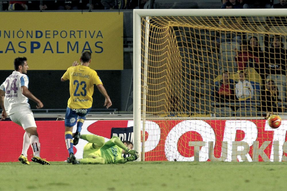 El defensa de la UD Las Palmas Dani Castellano (2i) y el portero Javi Varas (3i), no pueden evitar que el delantero paraguayo del Málaga Roque Santa Cruz (i) marque un gol.