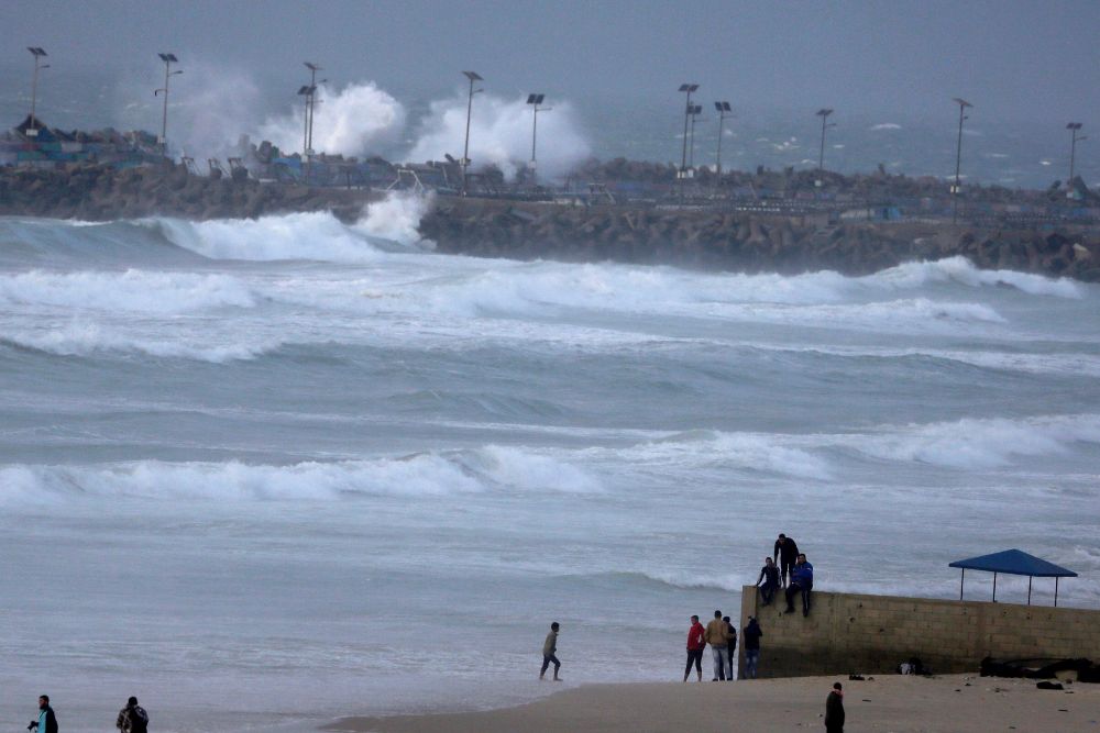 Palestinos caminan en la playa en un día de tormenta.