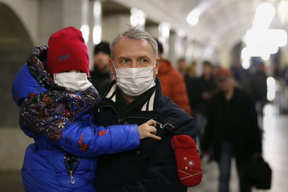 Un hombre y un niño se protegen la cara con mascarillas como prevención ante la gripe porcina en Moscú, Rusia.