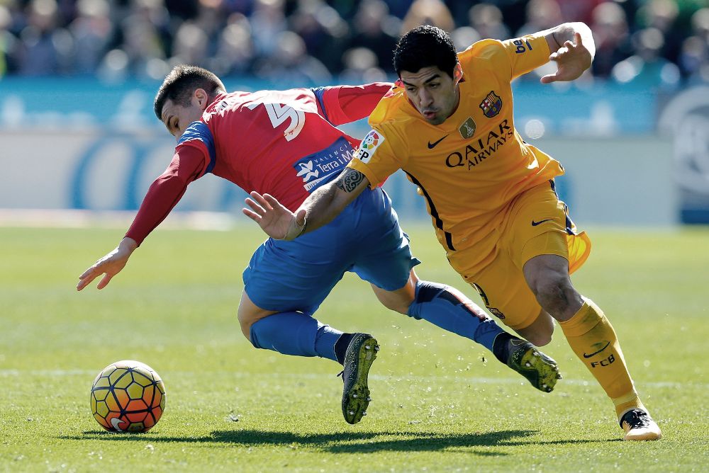El delantero uruguayo del FC Barcelona Luis Suárez (d) lucha un balón con el defensa del Levante "Toño".