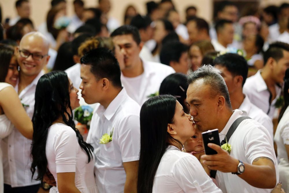 Parejas filipinas de recién casados se besan en una boda masiva.