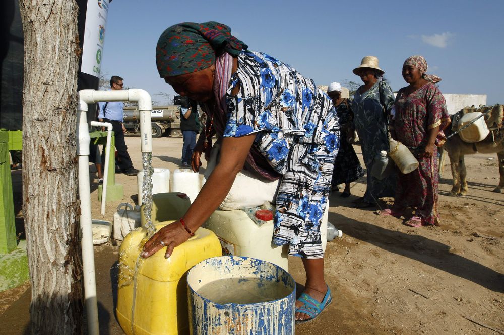 Indígenas Wayuu llenan recipientes con agua de pozos subterráneos en un resguardo indígena de Uribia, Colombia, país que también está padeciendo la sequía igual que partes de Venezuela.