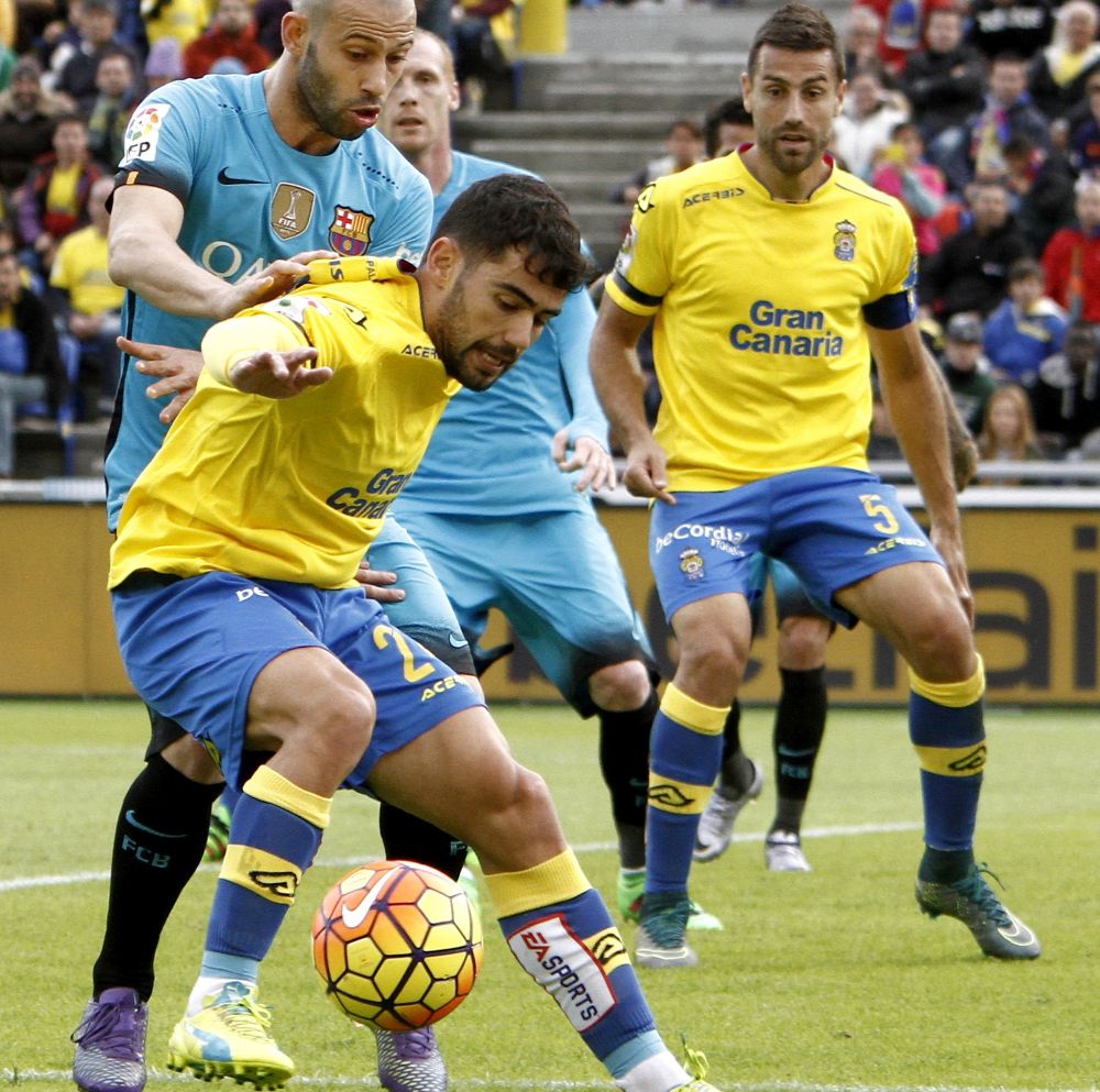 El centrocampista de la UD Las Palmas, Pedro Tanausu "Tana" (c), protege el balón ante el defensa argentino del FC Barcelona, Javier Mascherano (i), durante el partido de la vigésima quinta jornada de la Liga de Primera División.