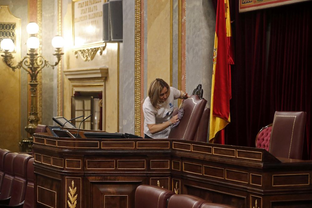 Empleadas de la limpieza ponen a punto el hemiciclo del Congreso de los Diputados de cara al debate de investidura del candidato socialista, Pedro Sánchez, que se inicia mañana.