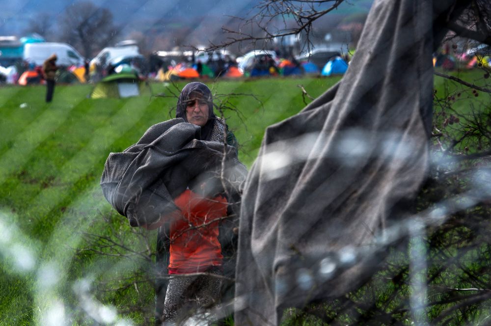 Una mujer recoge mantas colgadas en un árbol, tras secarse en Gevgelija (Macedonia) hoy, 4 de marzo de 2016.