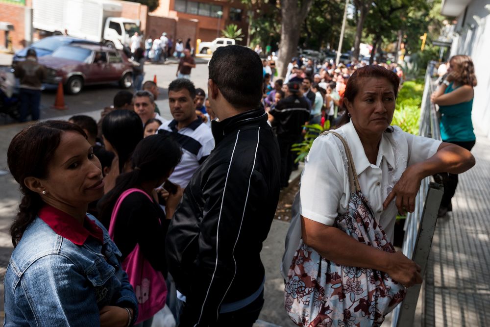Un grupo de personas aguardan en una fila para poder comprar enceres de primera necesidad en las inmediaciones de un local comercial en Caracas.