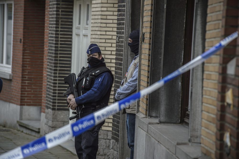 Policías belgas vigilan el exterior de una vivienda en el número 64 de la calle Busselenberg, en el distrito de Anderlecht-Bruselas, durante una redada hoy, 23 de marzo.