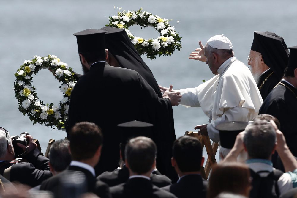 El papa Francisco y el patriarca ecuménico Bartolomé lanzan al mar coronas en memoria de los refugiados fallecidos.