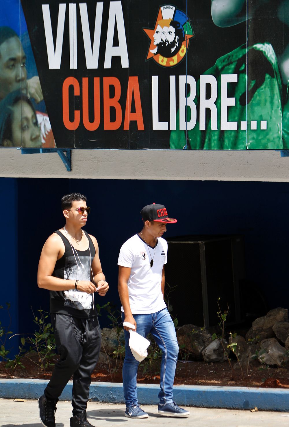 Dos jóvenes junto a un cartel alusivo a la Revolución cubana.