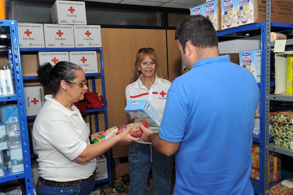 Dos voluntarias de Cruz Roja entregando alimentos en la capital tinerfeña.