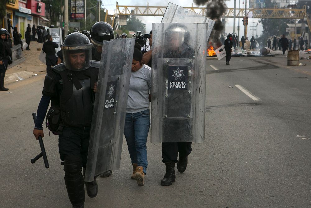 Policías federales conducen a una detenido en la ciudad de Oaxaca durante los enfrentamientos ayer, domingo, entre la Policía y los maestros para despejar la supercarretera Oaxaca-México y la carretera federal 190, en las inmediaciones del municipio de Nochixtlán en la región Mixteca.