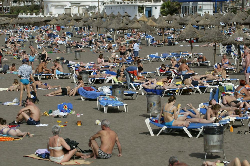 Decenas de turistas se bañan en la playa de Adeje.