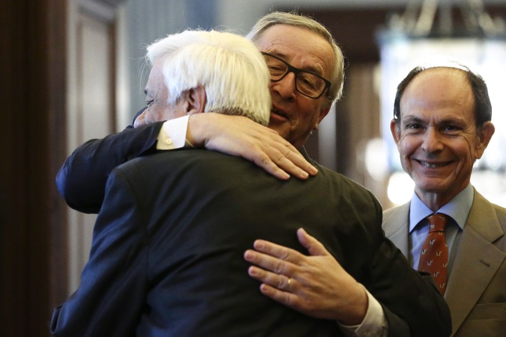 El presidente de la Comisión Europea, Jean Claude Juncker (c), abraza al presidente griego, Prokopis Pavlópulos, antes de su reunión en Atenas.