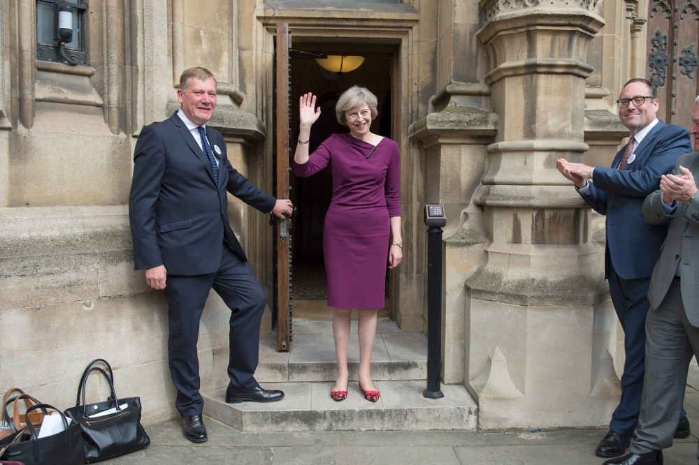 La ministra del Interior británica, Theresa May, saluda a la prensa a la salida del parlamento británico.