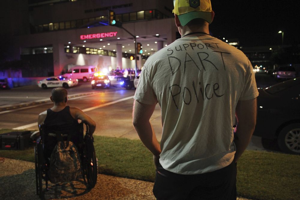 Un hombre luce una camiseta con un mensaje de apoyo a la policía mientras observa la entrada a emergencias del hospital Baylor Scott&White, donde fue llevado el cadáver de uno de los cinco agentes muertos.