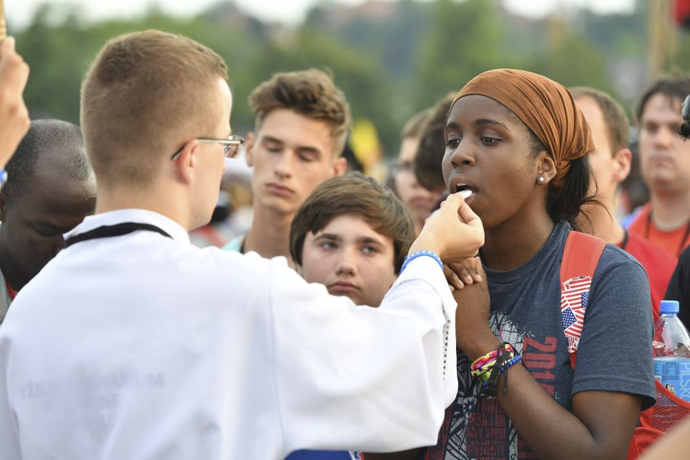 Varios peregrinos comulgan durante la santa misa inaugural de la XXXI Jornada Mundial de la Juventud (JMJ) en Cracovia.