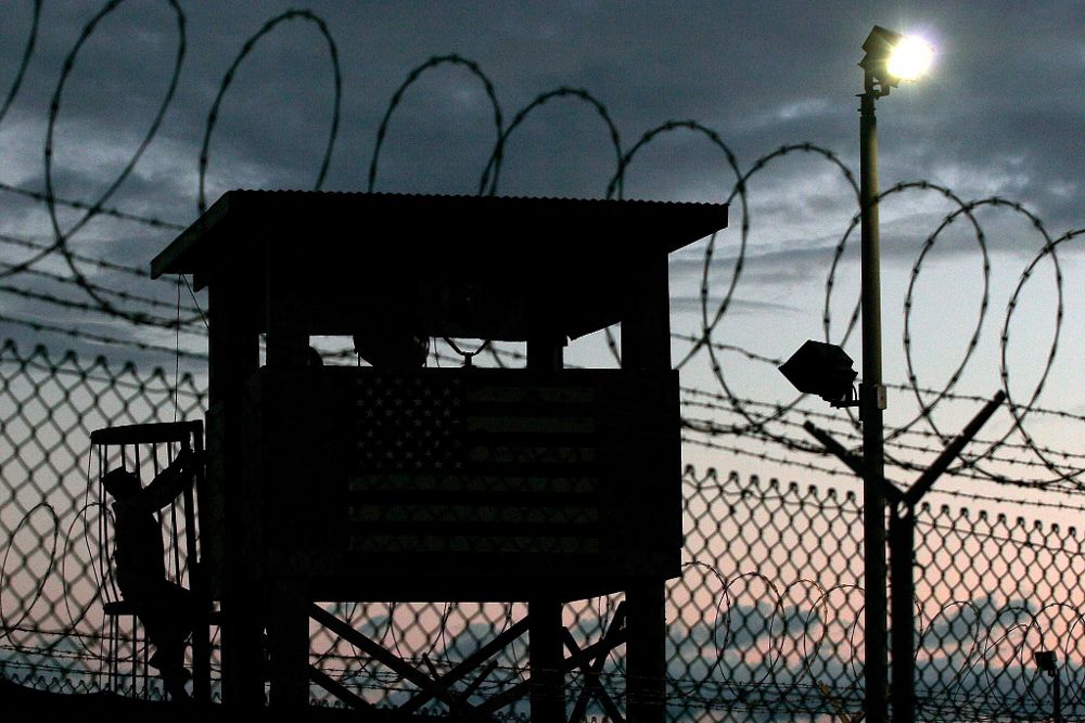 Fotografía de archivo de 2006, que muestra la silueta de un miembro de la Fuerza de Tarea Conjunta subiendo a una garita junto a un alambrado en un perímetro de seguridad en Campo Delta, estación naval en Guantánamo.