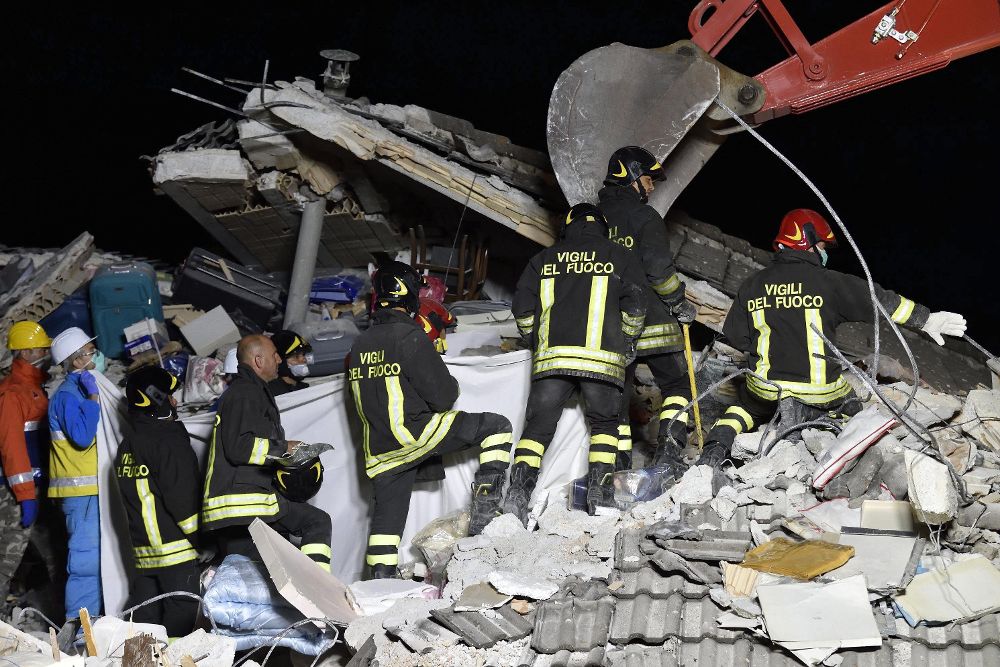 Los bomberos recuperan el cadáver de una víctima de entre los escombros de un edificio derrumbado en Amatrice.