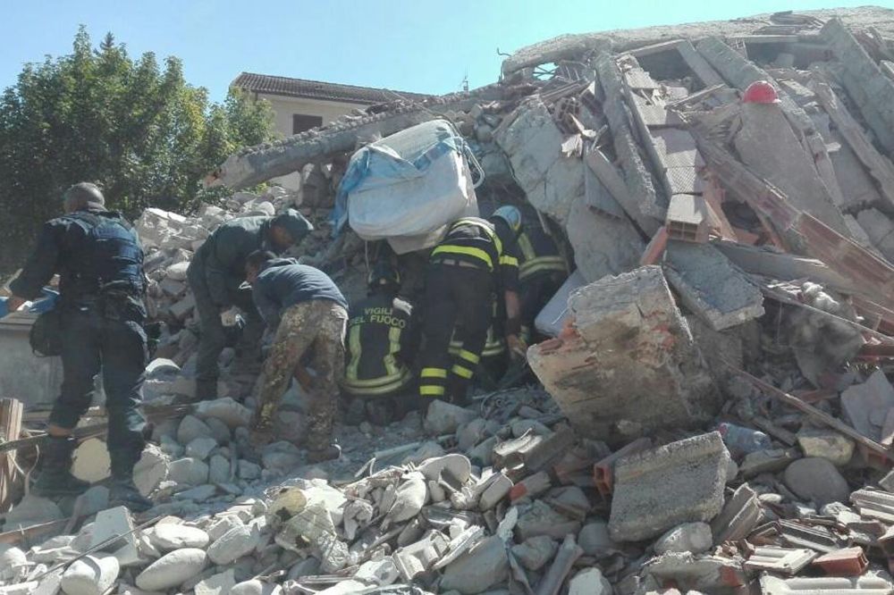 Varios bomberos buscan víctima entre los escombros de un edificio derrumbado en Amatrice.