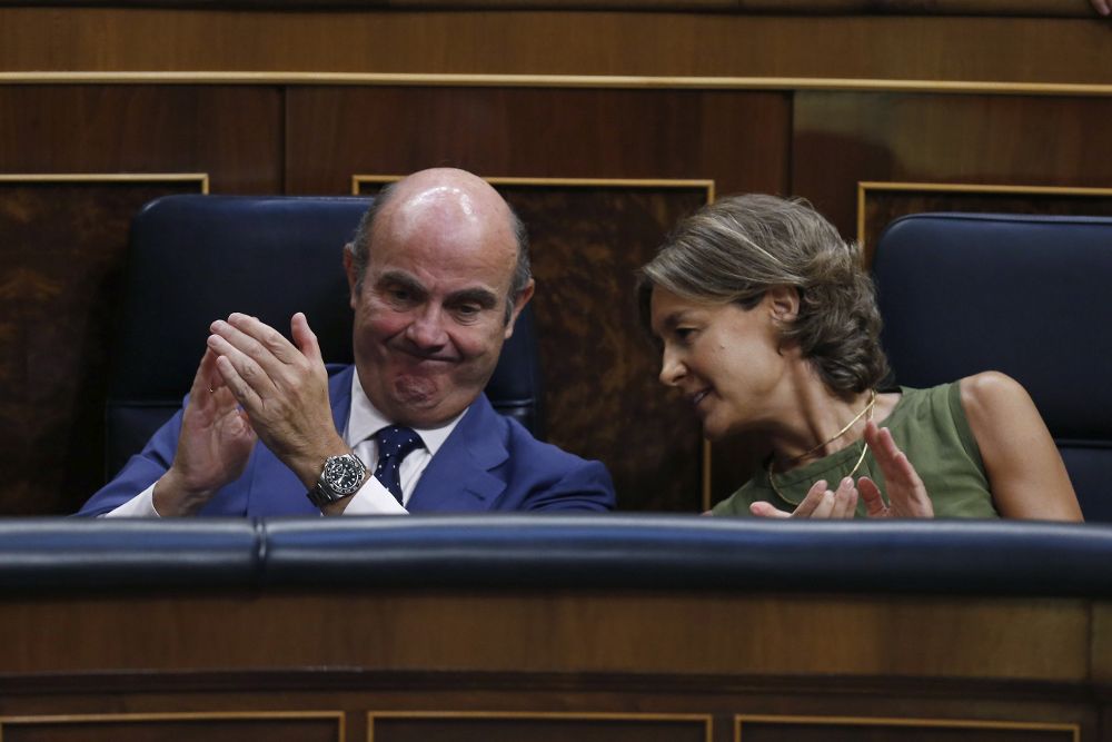 Los ministros en funciones de Economía, Luis de Guindos (i), y Agricultura y Pesca, Isabel García Tejerina (d), aplauden.