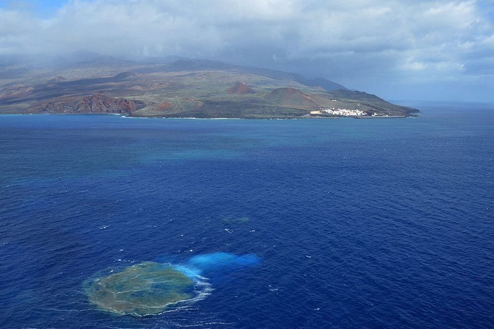 Imagen de la erupción submarina, en primer término, con la isla al fondo.