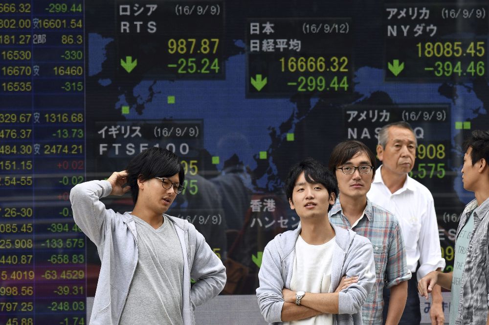 Japoneses se detienen frente a un monitor con la información de los mercados internacionales.