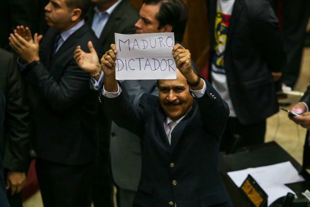 El diputado opositor Luis Silva sostiene un cartel contra el presidente venezolano, en el que se lee "Maduro dictador", durante una sesión de la Asamblea Nacional ayer, domingo.