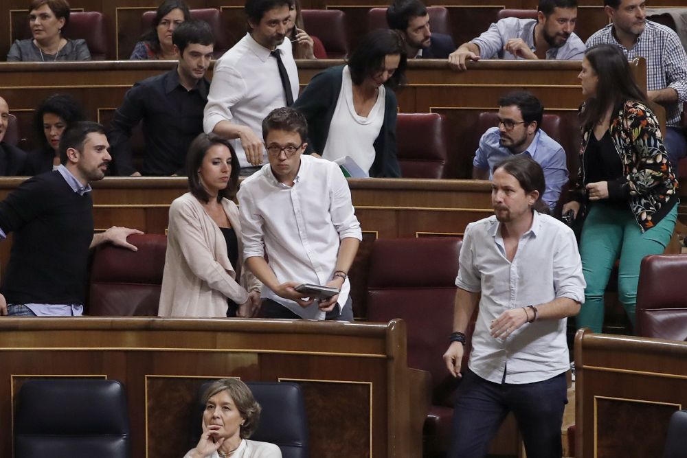 El líder de Podemos, Pablo Iglesias (d), y el resto de diputados de su grupo abandonan el hemiciclo en protesta por unas palabras del portavoz del PP, Rafael Hernando.
